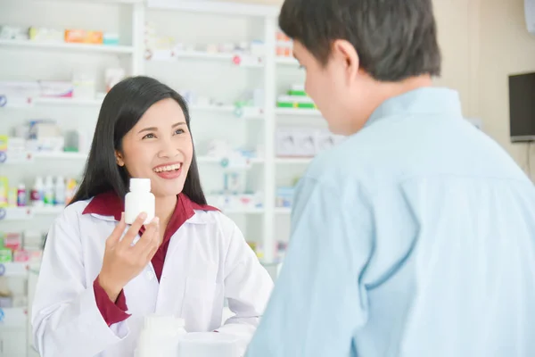 Souriant Asiatique Professionnel Jeune Pharmacien Montrant Bouteille Médicament Client Pharmacie — Photo