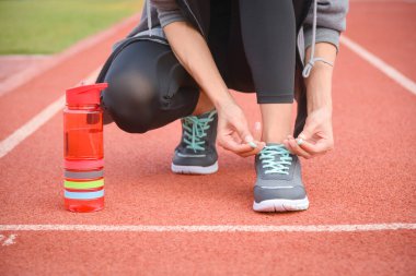 Sportif kadın, şehirde koşuya çıkmadan önce ayakkabı bağcıklarını bağlıyor..