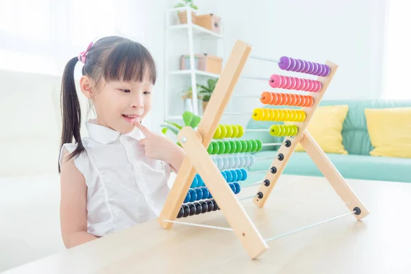 漂亮的亚洲女孩指望木材算盘在家里 儿童教育概念 免版税图库图片