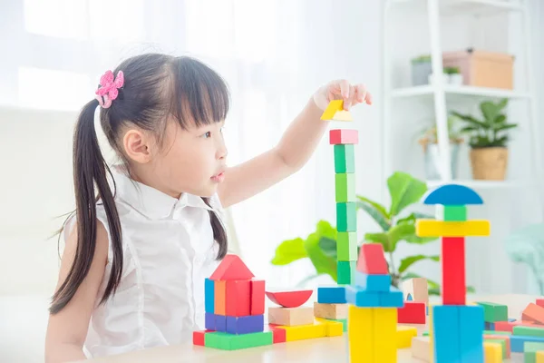 漂亮的亚洲小女孩在家里玩五彩缤纷的木块 儿童教育概念 免版税图库照片