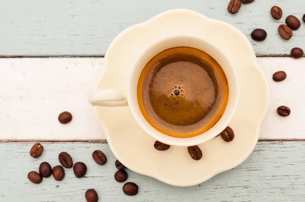 Kaffekopp og bønner på trebord – stockfoto