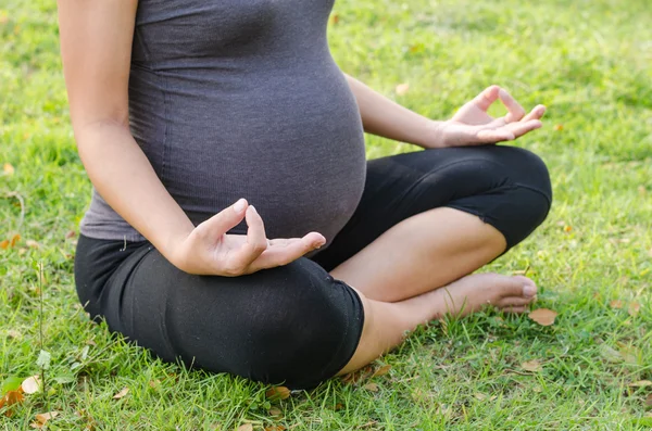 Mujer embarazada haciendo yoga en la naturaleza al aire libre . — Foto de Stock