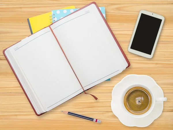 Cuaderno, lápiz, teléfono inteligente y taza de café en la mesa — Foto de Stock