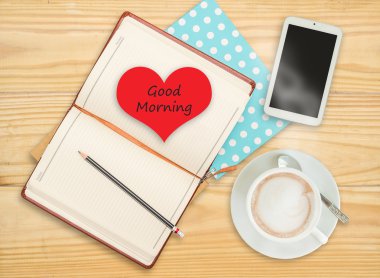 Günaydın defter ile akıllı telefon ve ahşap üzerine kahve fincanı üzerinde