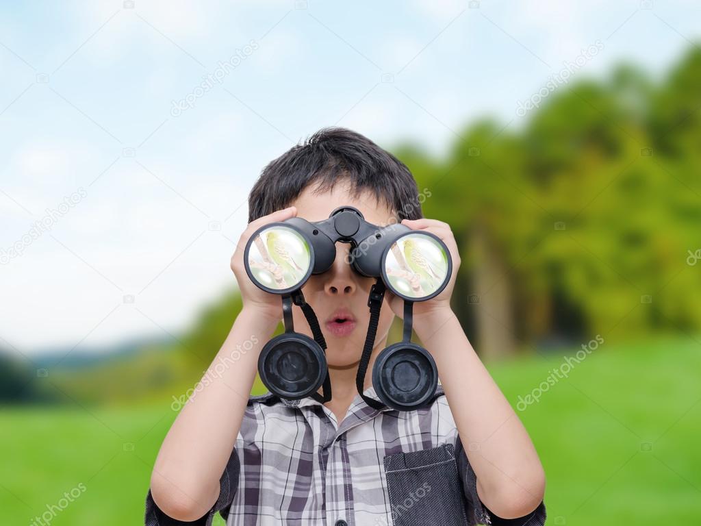 Boy using binoculars in forest