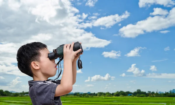 Boy using binoculars in field — Stock Photo, Image