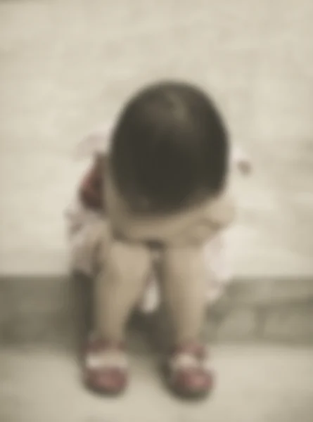 Маленькая грустная девочка сидит на полу одна — стоковое фото
