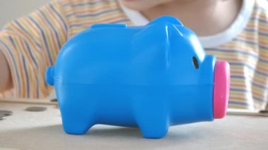 Çocuk domuz kumbarasına para koyuyor.