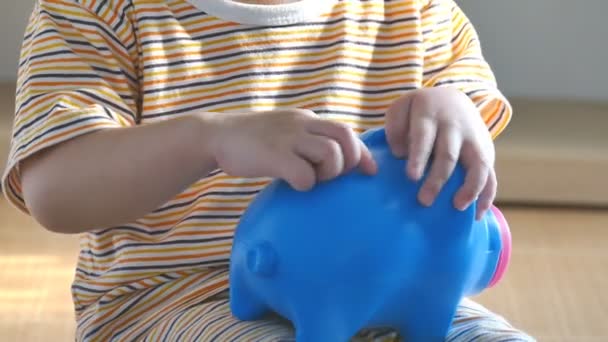 A gyerek pénzt tesz a malacperselybe. — Stock videók