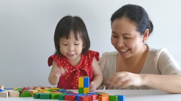 Девушка и мать играют с блоками на столе — стоковое видео