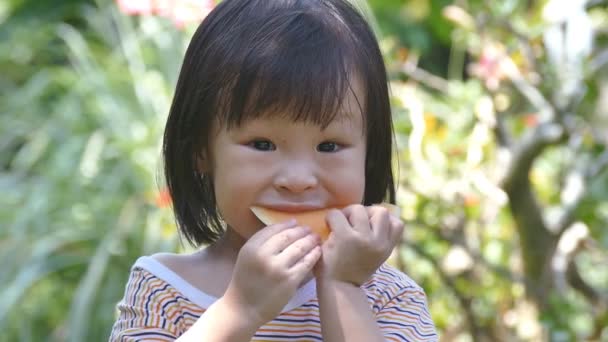 Mała dziewczynka, cieszyć się jedzeniem melona w parku — Wideo stockowe