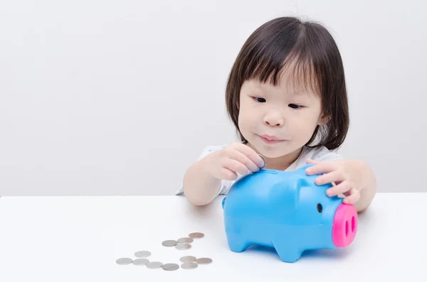 Little girl insert coin into piggy bank — Stock Photo, Image