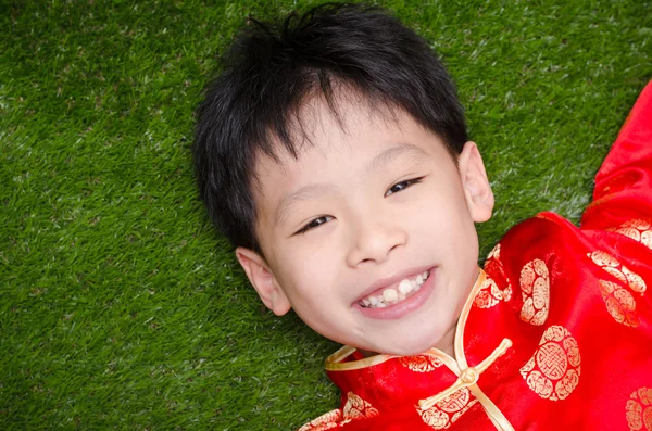 Boy in chinese costume lying on grass field — Stock Photo, Image