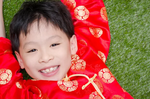 Boy in chinese costume lying on grass field — Stock Photo, Image