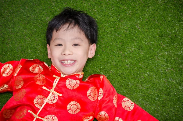 Garçon en costume chinois couché sur le champ d'herbe — Photo