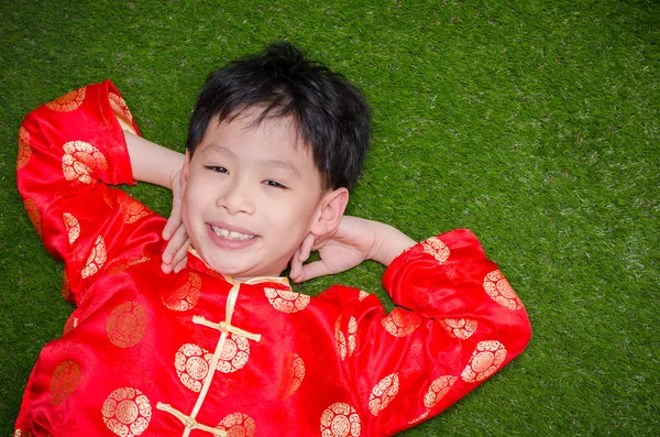 Jongen in Chinees kostuum liggend op grasveld — Stockfoto