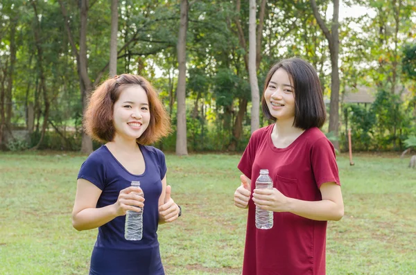 Meisjes houden van water fles en tonen duim omhoog — Stockfoto