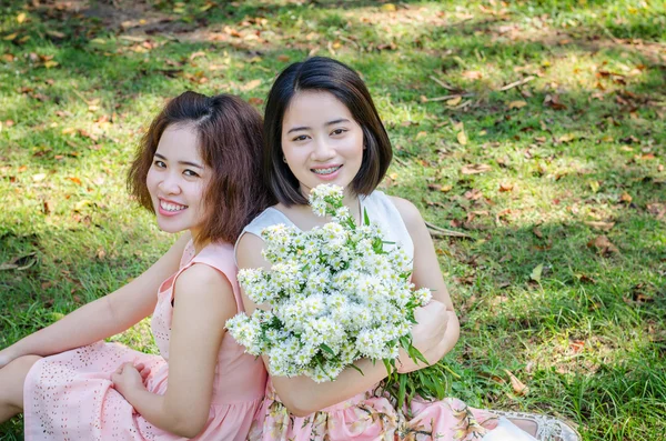 Jonge Aziatische vrouwen zittend op het gras in park — Stockfoto