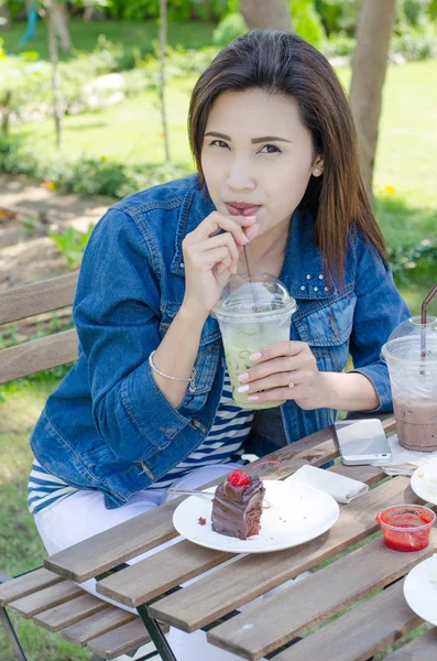 Mooie Aziatische vrouw drinken ijs greentea met taart — Stockfoto