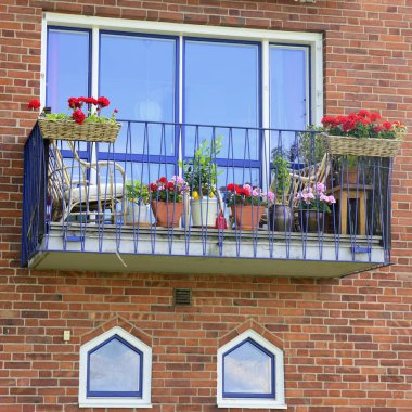 Modern apartman binasının mimari detayları. Sandalyeli ve çiçekli balkon