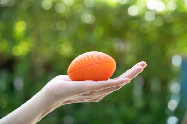 Frau Hält Orangefarbenen Ball Auf Grünem Hintergrund — Stockfoto