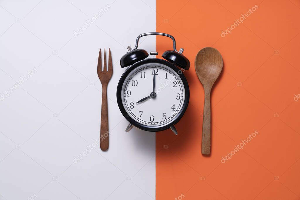 Food clock spoon and fork, Healthy food concept on white and orange background