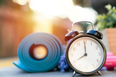 Çalar saat ve yoga paspası geçmişi, spor ve sağlıklı konsepti olan dambıl egzersizi zamanı.