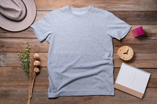 Mockup of a gray t-shirt blank shirt template with accessories on the wooden table background, lifestyle and travel concep