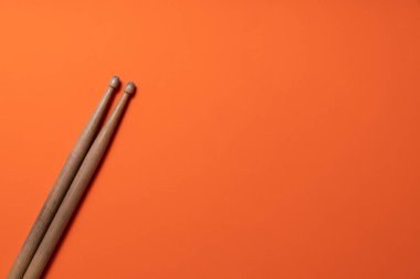 Drum stick on orange table background, top view, music concept