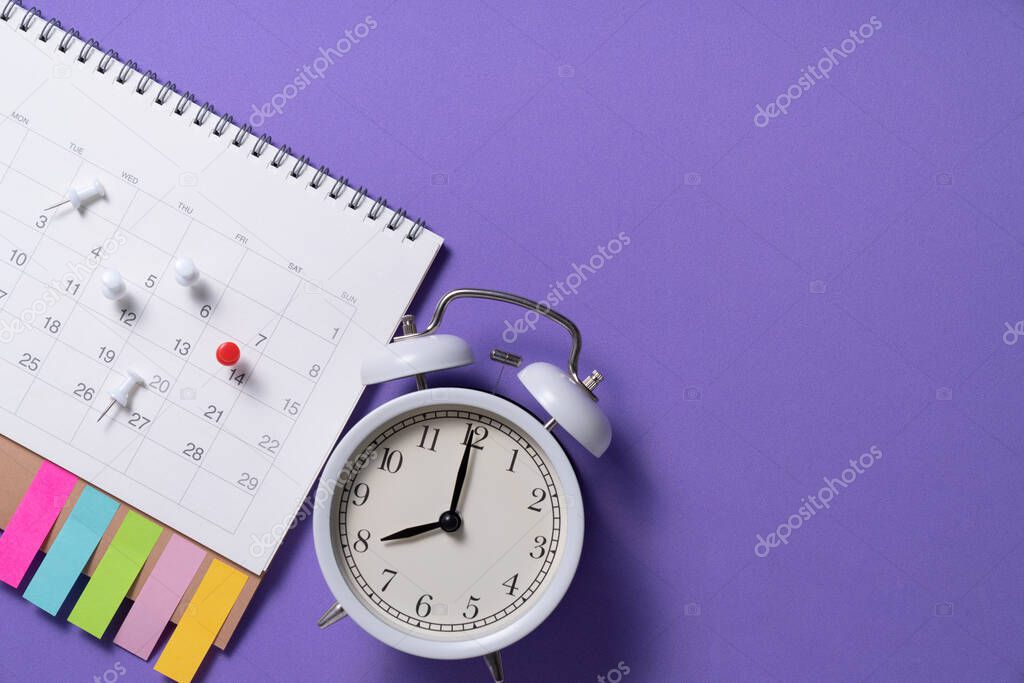 close up of clock and calendar on the purple table background, planning for business meeting or travel planning concept