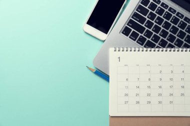 Takvimin, bilgisayarın, telefonun ve kalemin yeşil masa arka planında kapatılması, iş toplantısı veya seyahat planlama konsepti için planlama