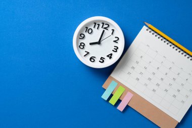 mavi masa arkaplanındaki takvim ve alarmın kapatılması, iş toplantısı ya da seyahat planlama konsepti