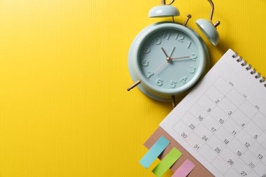 Sarı masa arkaplanındaki alarm saatini ve takvimi kapat, iş toplantısı ya da seyahat planlama konseptini planla