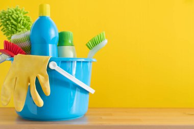 Ahşap masa üzerinde ev temizleme ürünü sarı arka plan, ev servisi veya temizlik konsepti