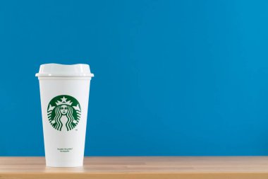 Bangkok, Tayland - 21 Mart 2021: Masadaki mavi arka planı olan beyaz bir Starbucks kahve fincanını kapat