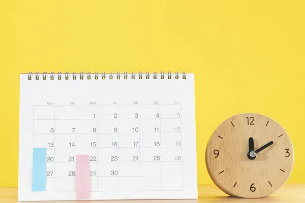 close up of calendar and clock on the table with yellow background, planning for business meeting or travel planning concept