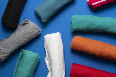 Mavi masa arkaplanındaki renkli t-shirtlerin kapağı, seyahat kavramı