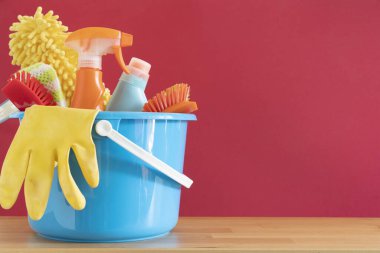 Ahşap masa üzerinde ev temizleme ürünü kırmızı arka plan, ev servisi veya temizlik konsepti