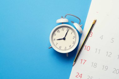 Takvimin kapatılması, mavi masa arkaplanındaki alarm saati, iş toplantısı ya da seyahat planlama konsepti