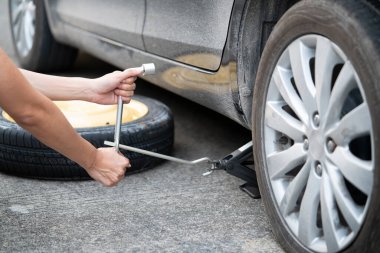 Yol kenarında tekerlek değiştiren bir kadın.