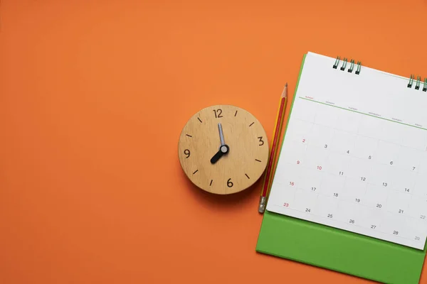 关闭橙色桌子背景上的日历和时钟 规划商务会议或旅行规划概念 — 图库照片