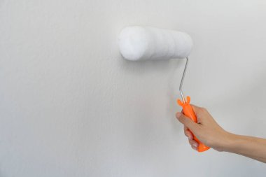 El işçisinin elinde fırça tutması duvardaki duvarları boyaması, boyaması ve tamir edilmesi.