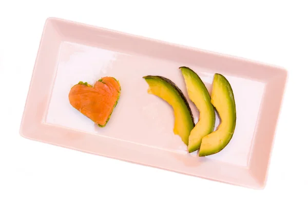 Tray with slices of avocado and salmon and avocado in a heart shape from above — Stock Photo, Image
