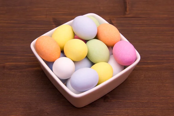 Gekleurde eieren op een vierkante kom op hout — Stockfoto