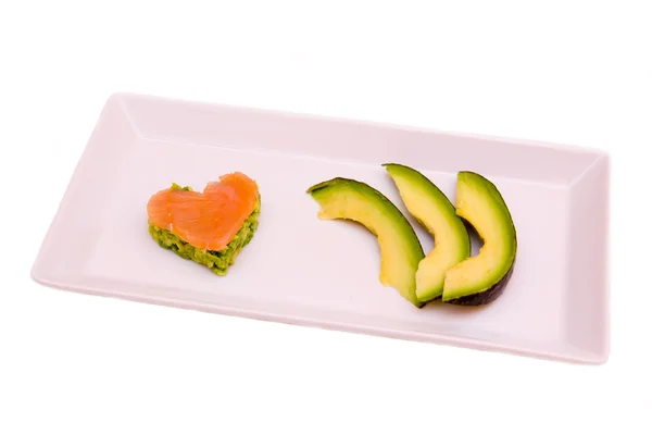 Tray with slices of avocado and salmon and avocado in a heart shape — Stock Photo, Image