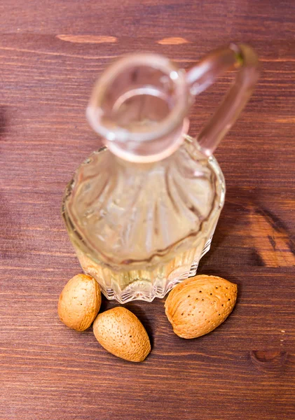 Botella con aceite sobre almendras de madera vista desde arriba — Foto de Stock