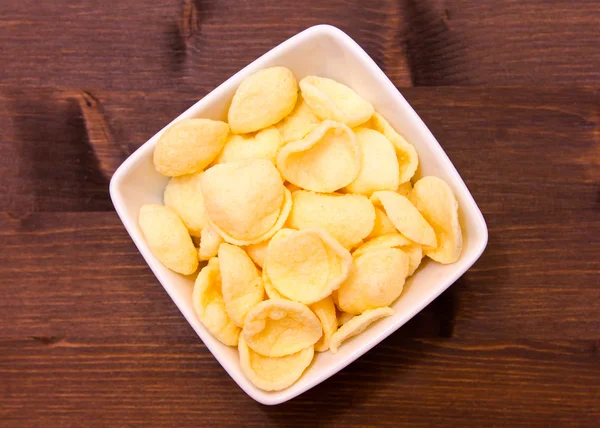 Potato snacks on a square bowl on wooden seen from above — Stock Photo, Image