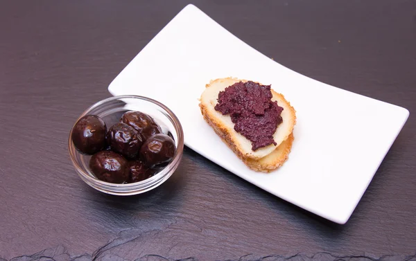 Scheibe Brot mit Olivenpaste auf Schiefer — Stockfoto