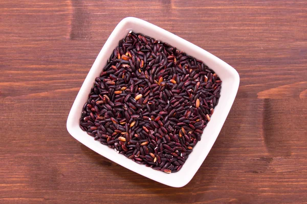 Black rice on a square bowl on wood seen from above — Stock Photo, Image