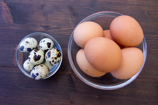 Tigelas com ovos de codorna e frango nas vistas superiores de madeira — Fotografia de Stock